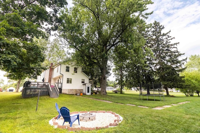 1193 Seneca St, Adrian, MI 49221 - view of grassy yard with a deck, an outdoor fire pit, stairway, a trampoline, and a shed