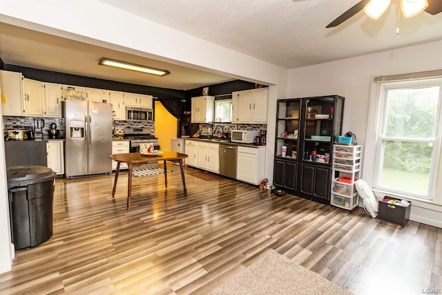 1193 Seneca St, Adrian, MI 49221 - kitchen with dark countertops, stainless steel appliances, decorative backsplash, ceiling fan, and wood finished floors