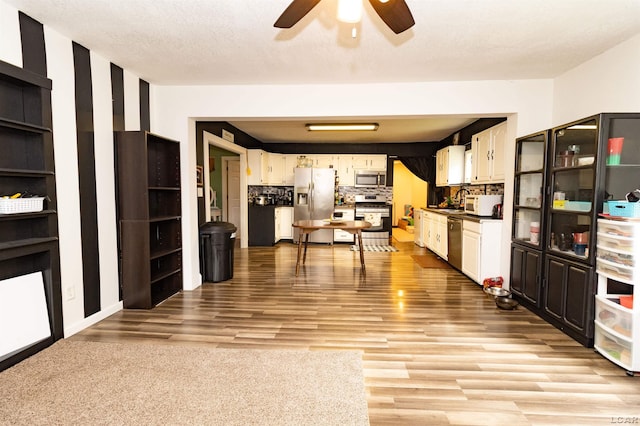 1193 Seneca St, Adrian, MI 49221 - kitchen with stainless steel appliances, ceiling fan, light wood-style flooring, white cabinetry, and dark countertops