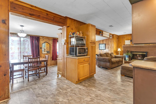 11585 Onsted Hwy, Brooklyn, MI 49230 - kitchen featuring wooden walls, stainless steel microwave, open floor plan, a fireplace, and brown cabinetry
