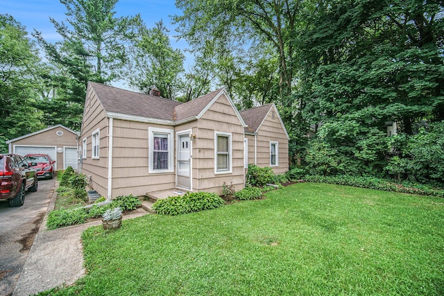 5097 Jackson Rd, Ann Arbor, MI 48103 - view of front of property with a chimney, a shingled roof, a front yard, an outdoor structure, and a detached garage
