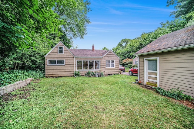 5097 Jackson Rd, Ann Arbor, MI 48103 - rear view of property featuring a shingled roof, a yard, and a chimney