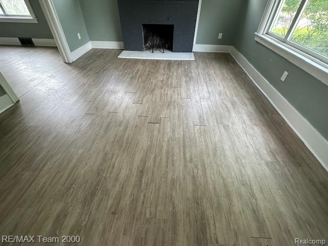 214 E Hazelhurst St, Ferndale, MI 48220 - unfurnished living room with a fireplace with raised hearth and dark wood-style flooring