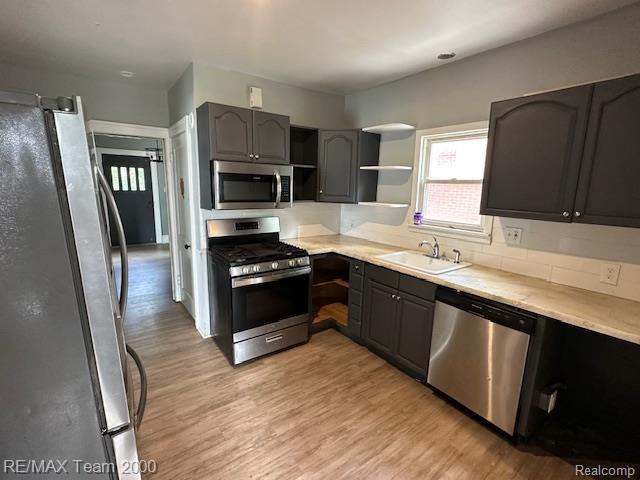 214 E Hazelhurst St, Ferndale, MI 48220 - kitchen with appliances with stainless steel finishes, open shelves, light wood finished floors, light countertops, and backsplash