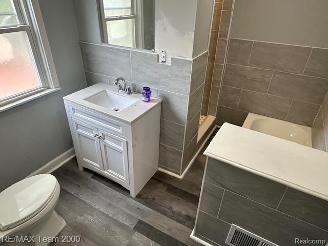 214 E Hazelhurst St, Ferndale, MI 48220 - full bathroom with vanity, tiled shower, wood finished floors, and tile walls