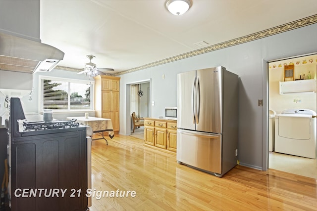 209 3rd St, Linwood, MI 48634 - kitchen with stainless steel appliances, wall chimney range hood, light wood finished floors, and washer and clothes dryer