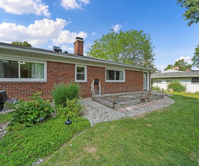 700 Devonshire Rd, Fowlerville, MI 48836 - back of property with a lawn, a chimney, brick siding, and a vegetable garden