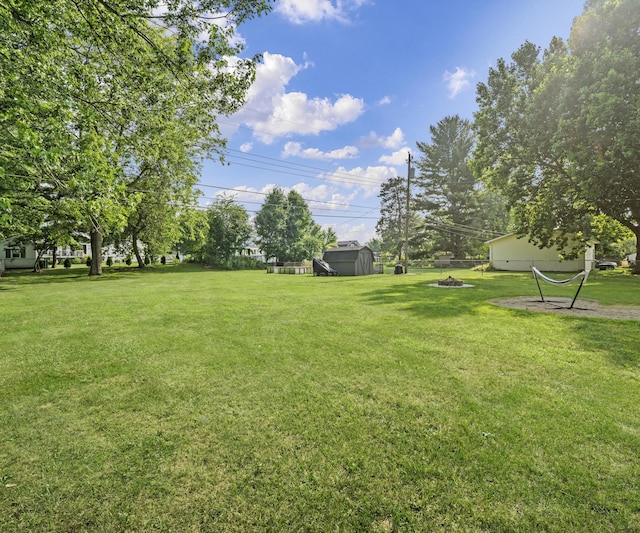700 Devonshire Rd, Fowlerville, MI 48836 - view of grassy yard featuring a storage unit and a fire pit