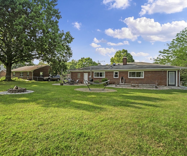 700 Devonshire Rd, Fowlerville, MI 48836 - rear view of property featuring an outdoor fire pit, a lawn, brick siding, and a patio area