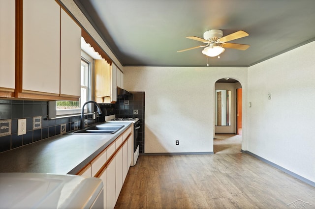 2113 Bock Rd, Saginaw, MI 48603 - kitchen featuring arched walkways, light wood-style flooring, decorative backsplash, white gas range, and a ceiling fan