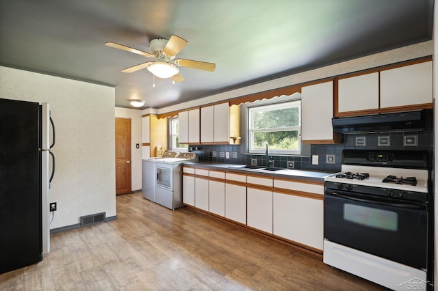 2113 Bock Rd, Saginaw, MI 48603 - kitchen featuring gas stove, freestanding refrigerator, washer / clothes dryer, light wood-style flooring, and white cabinetry