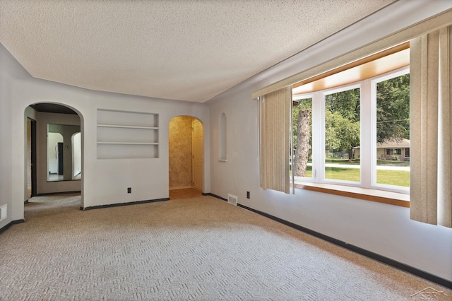 2113 Bock Rd, Saginaw, MI 48603 - empty room featuring healthy amount of natural light, arched walkways, carpet floors, built in shelves, and a textured ceiling