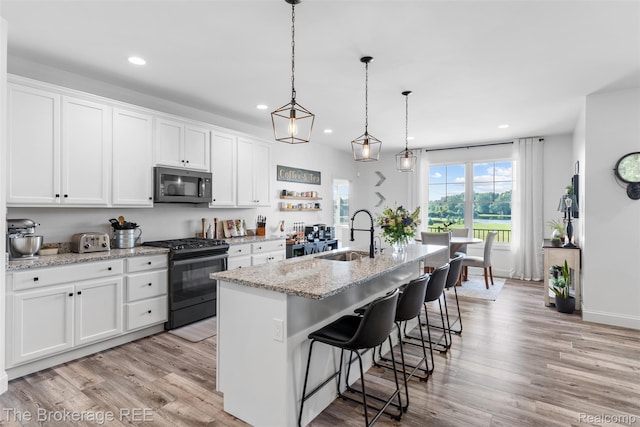 6264 Hidden Forrest, Swartz Creek, MI 48473 - kitchen with recessed lighting, gas stove, stainless steel microwave, light wood-type flooring, and white cabinets