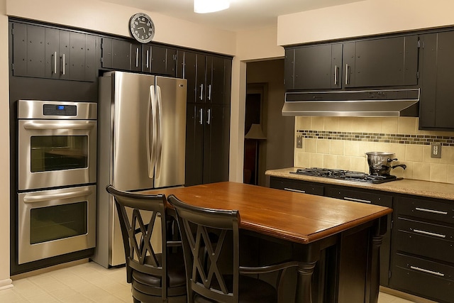 28740 Tavistock Trl, Southfield, MI 48034 - kitchen with appliances with stainless steel finishes, under cabinet range hood, backsplash, butcher block counters, and a kitchen island