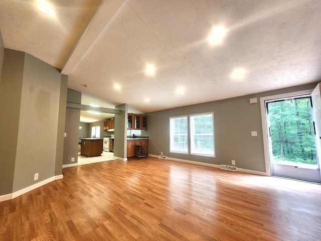 6580 Deerfield Trl, Lake, MI 48632 - unfurnished living room with a textured ceiling, light wood finished floors, and lofted ceiling