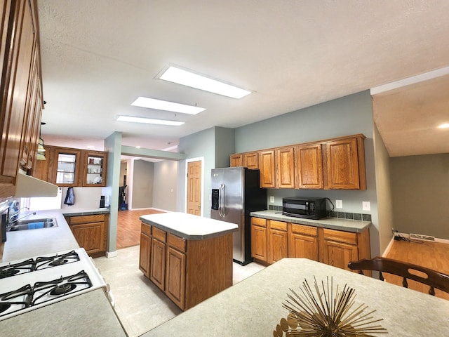 6580 Deerfield Trl, Lake, MI 48632 - kitchen with brown cabinetry, a center island, stainless steel fridge, and black microwave