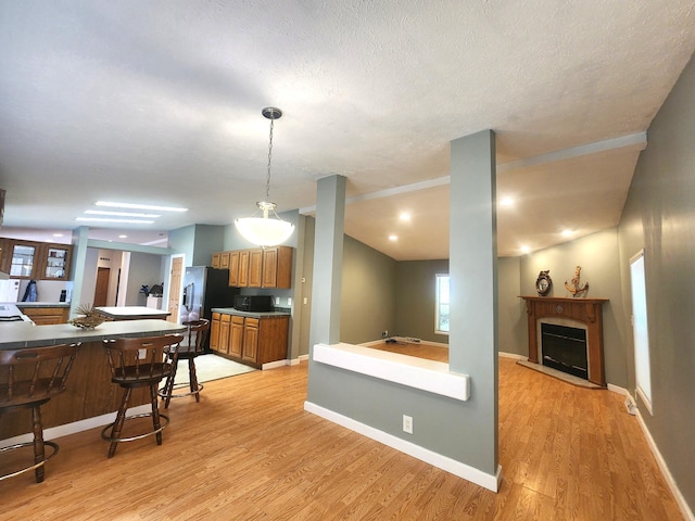 6580 Deerfield Trl, Lake, MI 48632 - kitchen featuring a kitchen breakfast bar, light wood-style floors, brown cabinetry, a fireplace, and stainless steel fridge