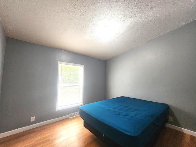 6580 Deerfield Trl, Lake, MI 48632 - bedroom with light wood-style flooring and a textured ceiling