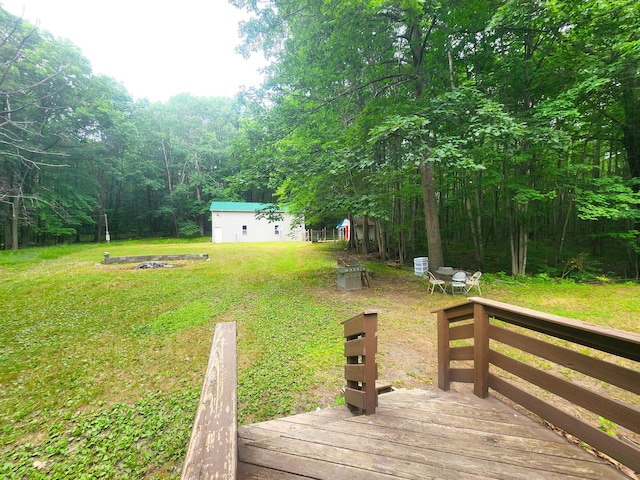 6580 Deerfield Trl, Lake, MI 48632 - view of green lawn featuring a wooden deck, a forest view, and an outdoor structure