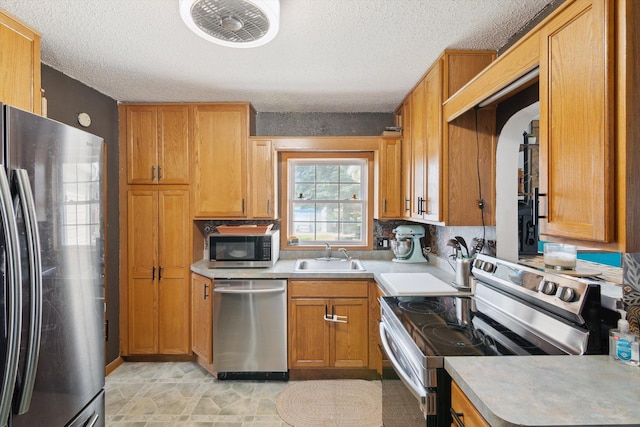 1903 Bucholtz Hwy, Deerfield, MI 49238 - kitchen with appliances with stainless steel finishes, a textured ceiling, light countertops, arched walkways, and brown cabinets