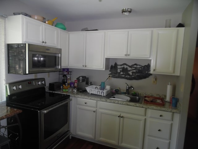 951-955 Bellevue Ave St, Jackson, MI 49202 - kitchen featuring appliances with stainless steel finishes, white cabinets, and light stone counters