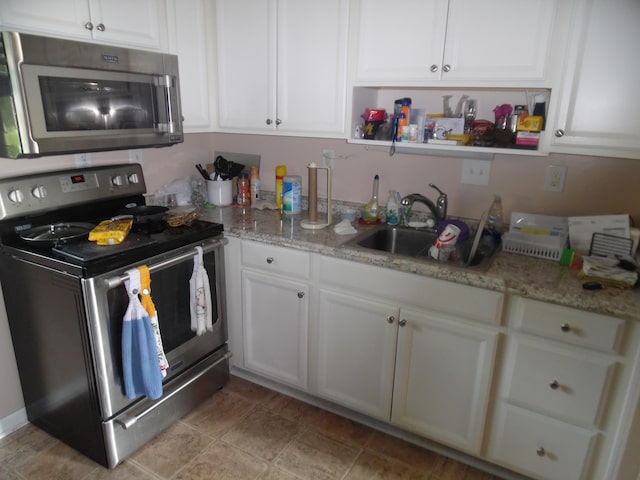 951-955 Bellevue Ave St, Jackson, MI 49202 - kitchen with stainless steel appliances, white cabinets, and light stone countertops