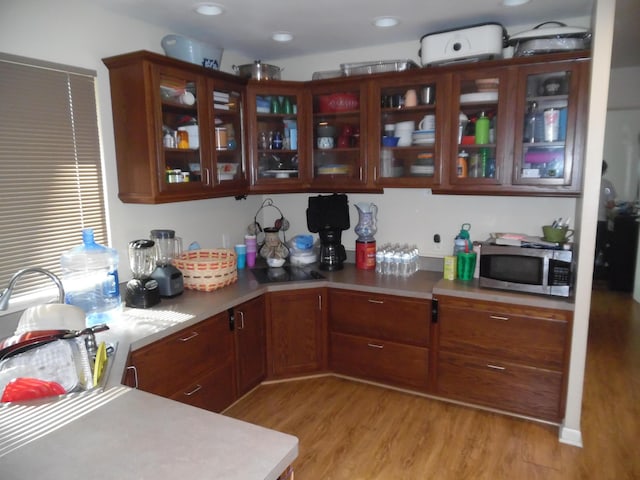 954 Concord Blvd, Jackson, MI 49202 - kitchen featuring light wood-style floors, light countertops, glass insert cabinets, and stainless steel microwave