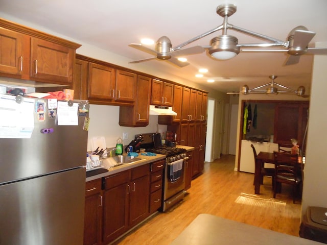 954 Concord Blvd, Jackson, MI 49202 - kitchen featuring appliances with stainless steel finishes, ceiling fan, light wood-type flooring, under cabinet range hood, and brown cabinetry