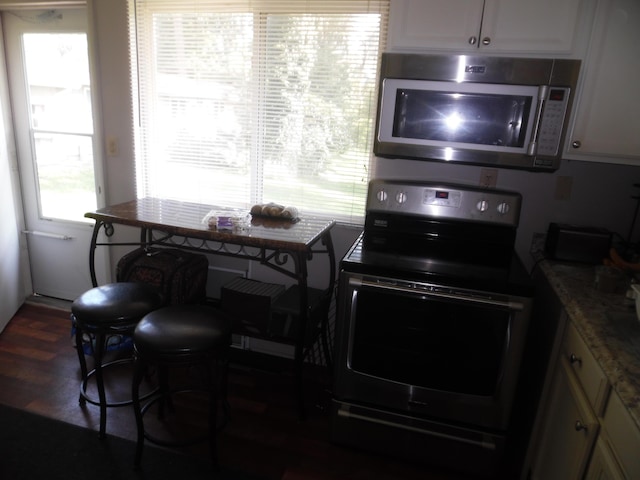 954 Concord Blvd, Jackson, MI 49202 - kitchen with black electric range, stainless steel microwave, white cabinetry, and dark wood-type flooring