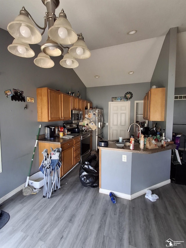 3017 3rd St, Monroe, MI 48162 - kitchen featuring lofted ceiling, wood finished floors, appliances with stainless steel finishes, brown cabinets, and dark countertops