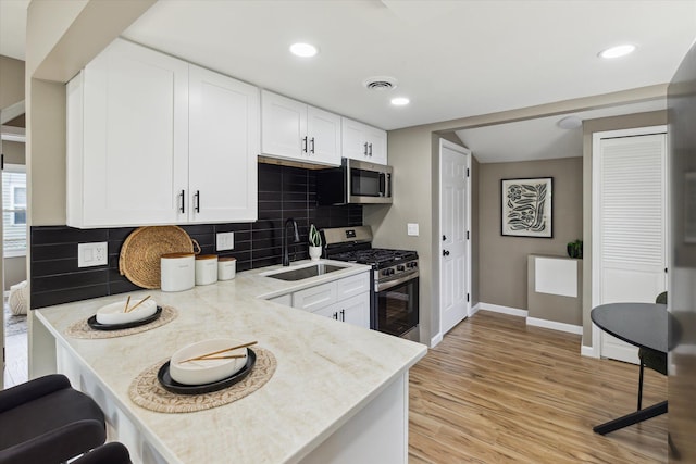 233 Outer Ln, Ypsilanti, MI 48198 - kitchen with appliances with stainless steel finishes, white cabinets, tasteful backsplash, light wood finished floors, and a kitchen bar