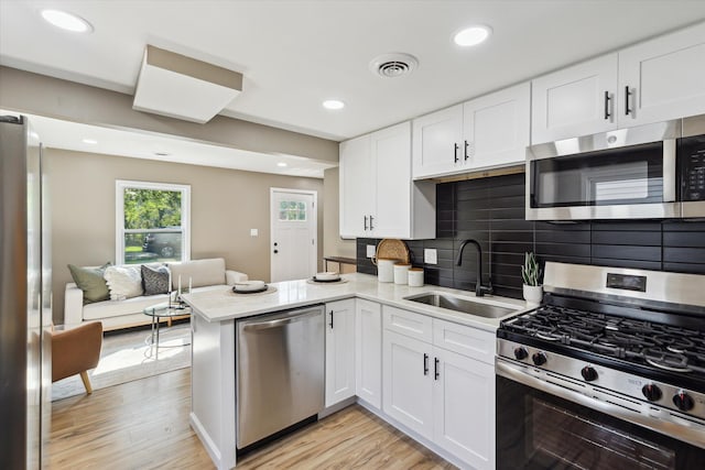 233 Outer Ln, Ypsilanti, MI 48198 - kitchen featuring stainless steel appliances, a peninsula, white cabinets, light wood finished floors, and backsplash