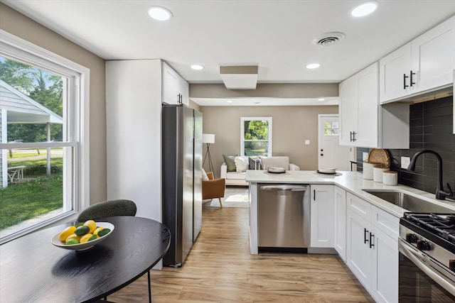 233 Outer Ln, Ypsilanti, MI 48198 - kitchen with stainless steel appliances, white cabinetry, light wood-type flooring, recessed lighting, and decorative backsplash