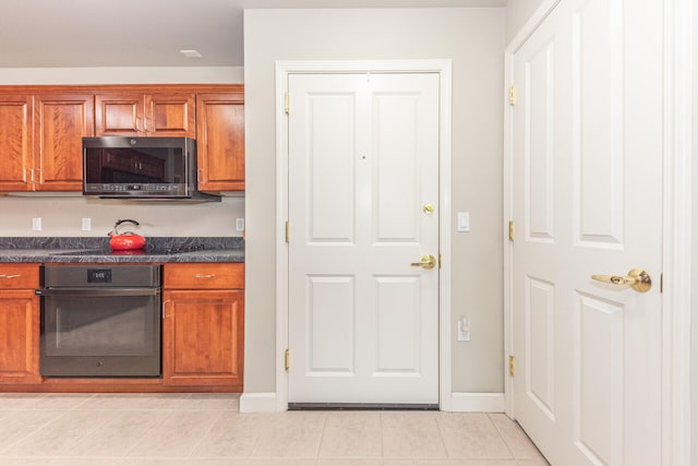 827 Asa Gray Dr Unit 257, Ann Arbor, MI 48105 - kitchen featuring oven, dark countertops, stainless steel microwave, light tile patterned floors, and brown cabinets