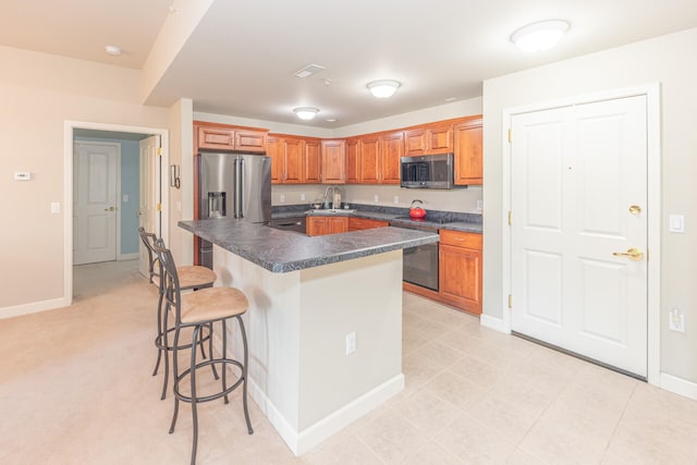 827 Asa Gray Dr Unit 257, Ann Arbor, MI 48105 - kitchen featuring dark countertops, a kitchen bar, appliances with stainless steel finishes, brown cabinetry, and a kitchen island