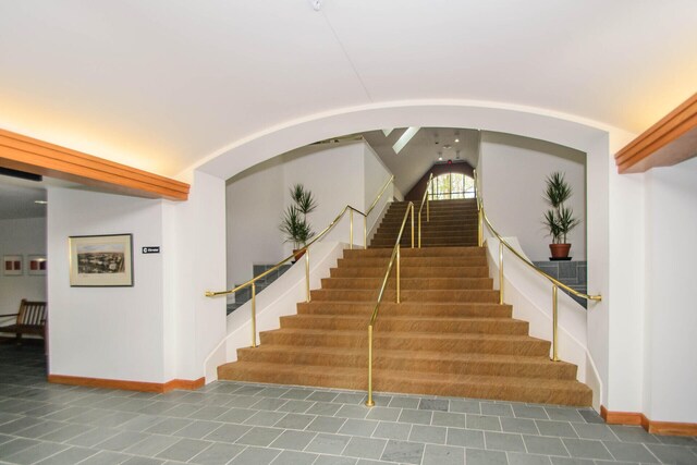 827 Asa Gray Dr Unit 257, Ann Arbor, MI 48105 - staircase featuring lofted ceiling, tile patterned floors, and arched walkways