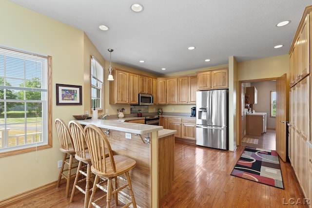 5726 Wolf Creek Hwy, Adrian, MI 49221 - kitchen with appliances with stainless steel finishes, a peninsula, plenty of natural light, a breakfast bar, and recessed lighting