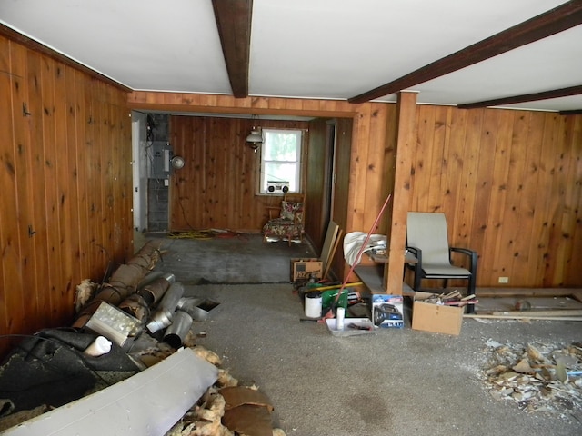 misc room featuring carpet, beam ceiling, and wood walls