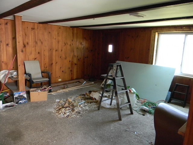 interior space featuring beamed ceiling, carpet floors, and wooden walls