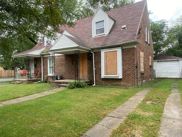 view of front facade with covered porch, an outbuilding, a garage, and a front lawn