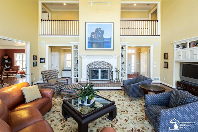 living room featuring a fireplace, a towering ceiling, hardwood / wood-style flooring, and crown molding