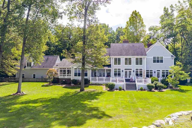 back of house with a lawn, a sunroom, and a wooden deck