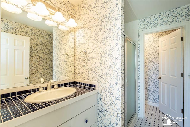 bathroom featuring a shower with door and vanity