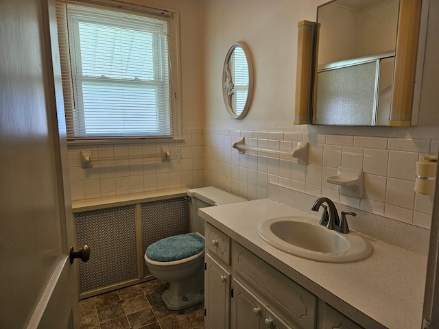 bathroom featuring vanity, toilet, and tile walls