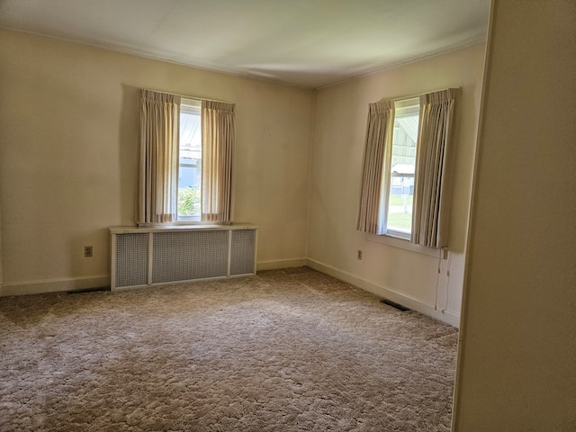 carpeted spare room with radiator heating unit and a wealth of natural light