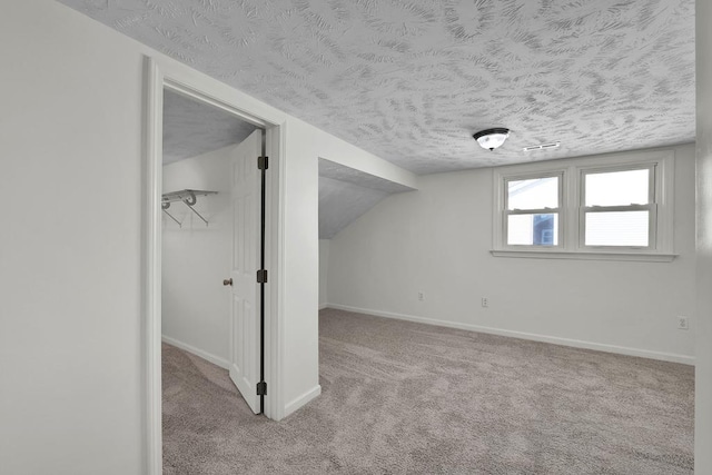 additional living space with lofted ceiling, light carpet, and a textured ceiling