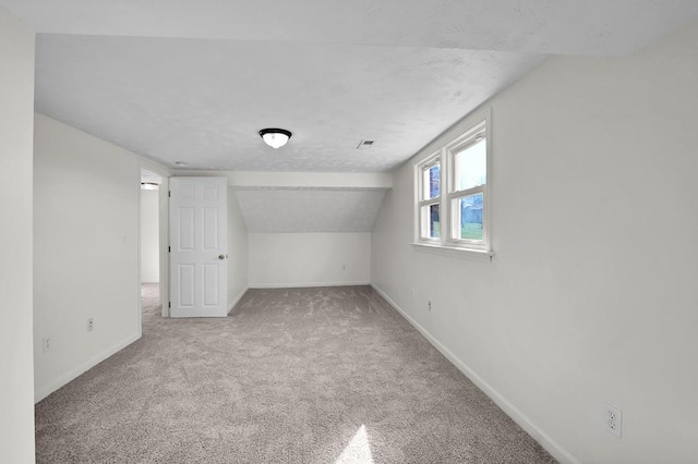 bonus room featuring lofted ceiling, carpet flooring, and a textured ceiling