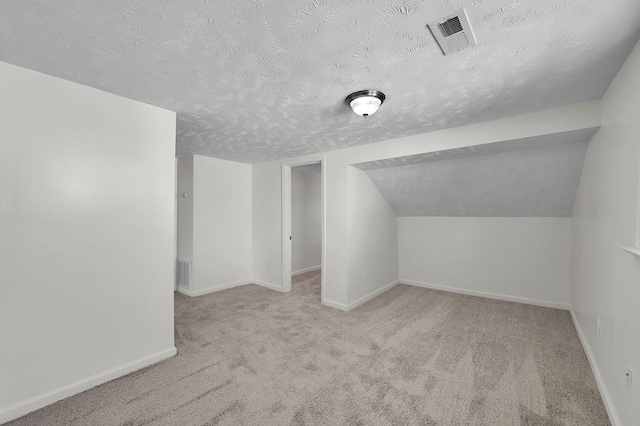 additional living space featuring light colored carpet, lofted ceiling, and a textured ceiling