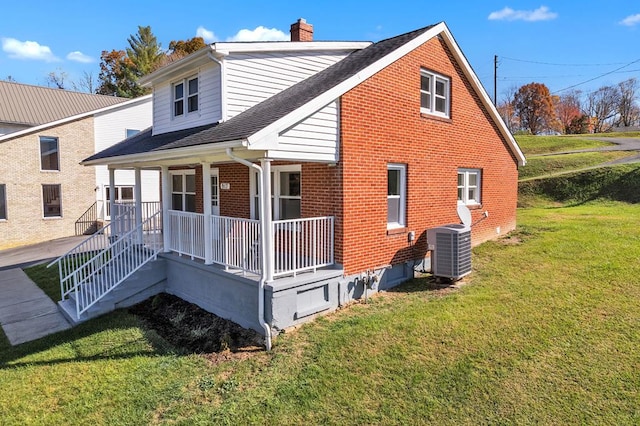 rear view of property featuring central AC unit, a lawn, and a porch