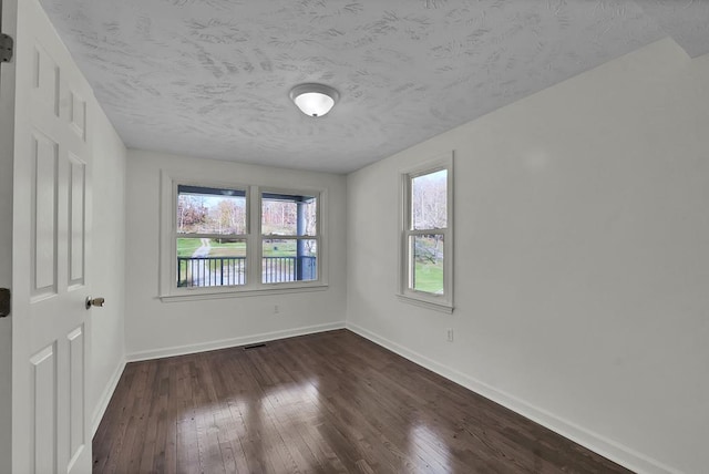 empty room featuring dark hardwood / wood-style flooring and a textured ceiling